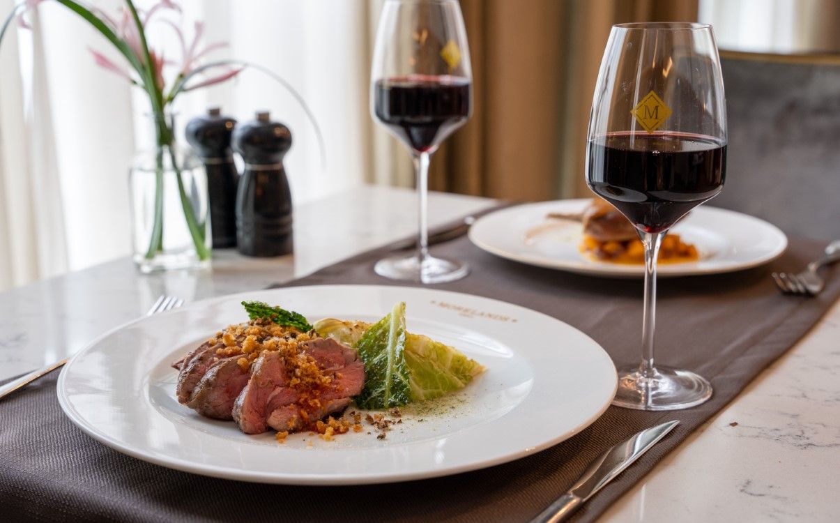 Table set with two dishes and two glasses of wine in Morelands Grill