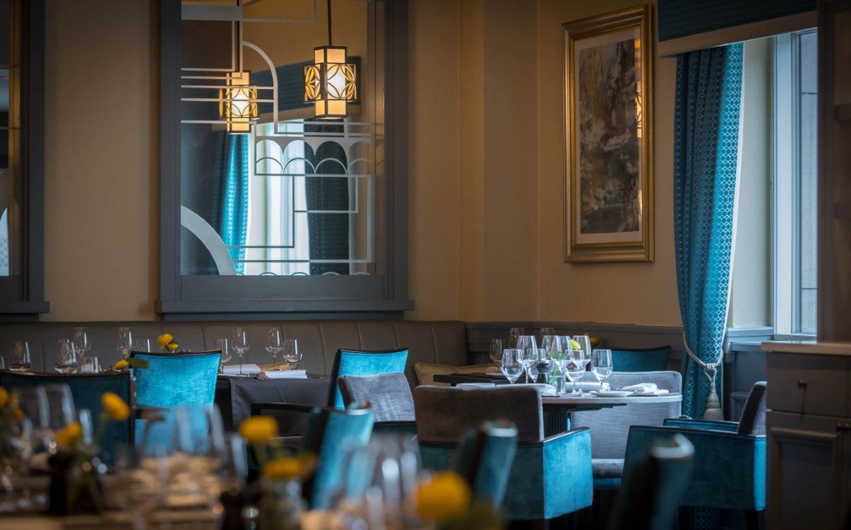 Restaurant set for dinner with tables and blue chairs in Morelands Grill