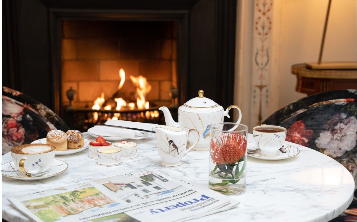 Table set with tea, scones and newspaper next to fireplace in The College Green Hotel Dublin