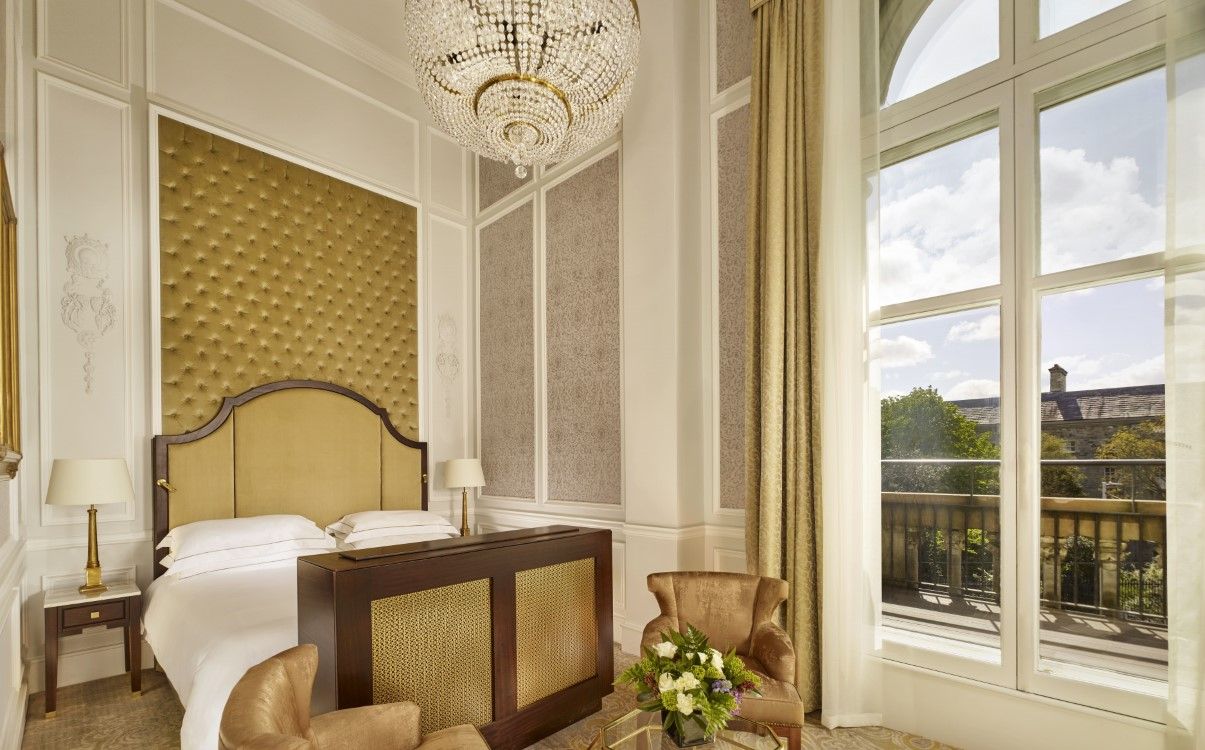 Large presidential suite bedroom with chandelier and large window with view in The College Green Hotel Dublin